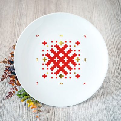 Balts šķīvis ar sarkanu un zelta Latvijas ornamentu
