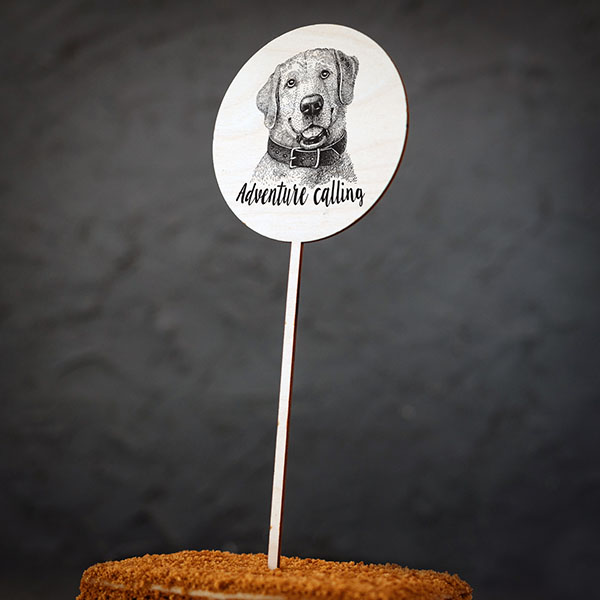 Dekoratīvs kūku dekors ar suņa zīmējumu un tekstu: "Adventure calling"