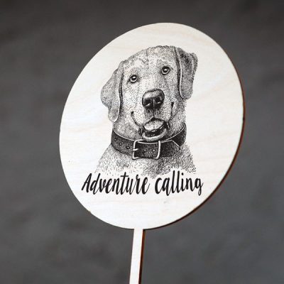 Dekoratīvs kūku dekors ar suņa zīmējumu un tekstu: "Adventure calling"