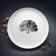 Lielais šķīvis ar melnu ozola zīmējumu un sudrabotu tekstu: "Ar saknēm zemē, ar lapām debesīm"