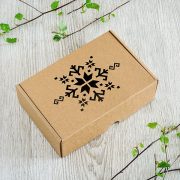 Kartona kaste ar lāzergravētu latvju zīmes zīmējumu.