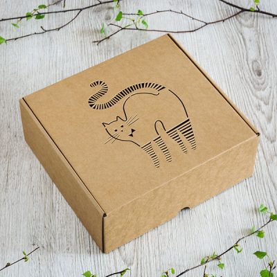Kartona kaste ar lāzergravētu strīpaina kaķa zīmējumu.