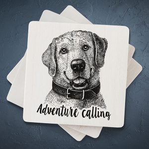 Balts mazs magnēts ar melnu suņa zīmējumu un tekstu: "Adventure calling"