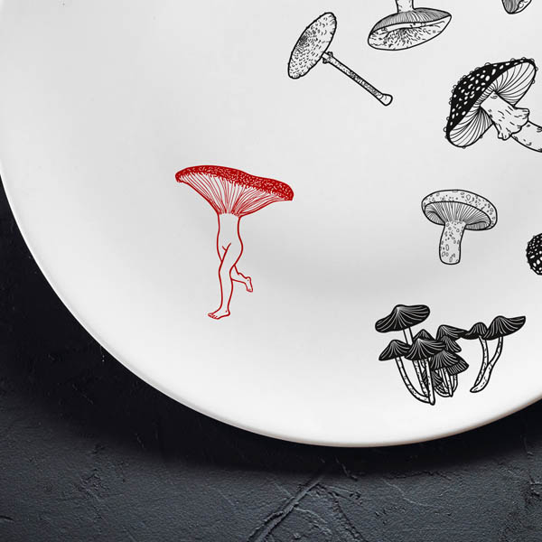 Vidējais šķīvis ar melnu sēņu zīmējumu un sarkanu elementu.